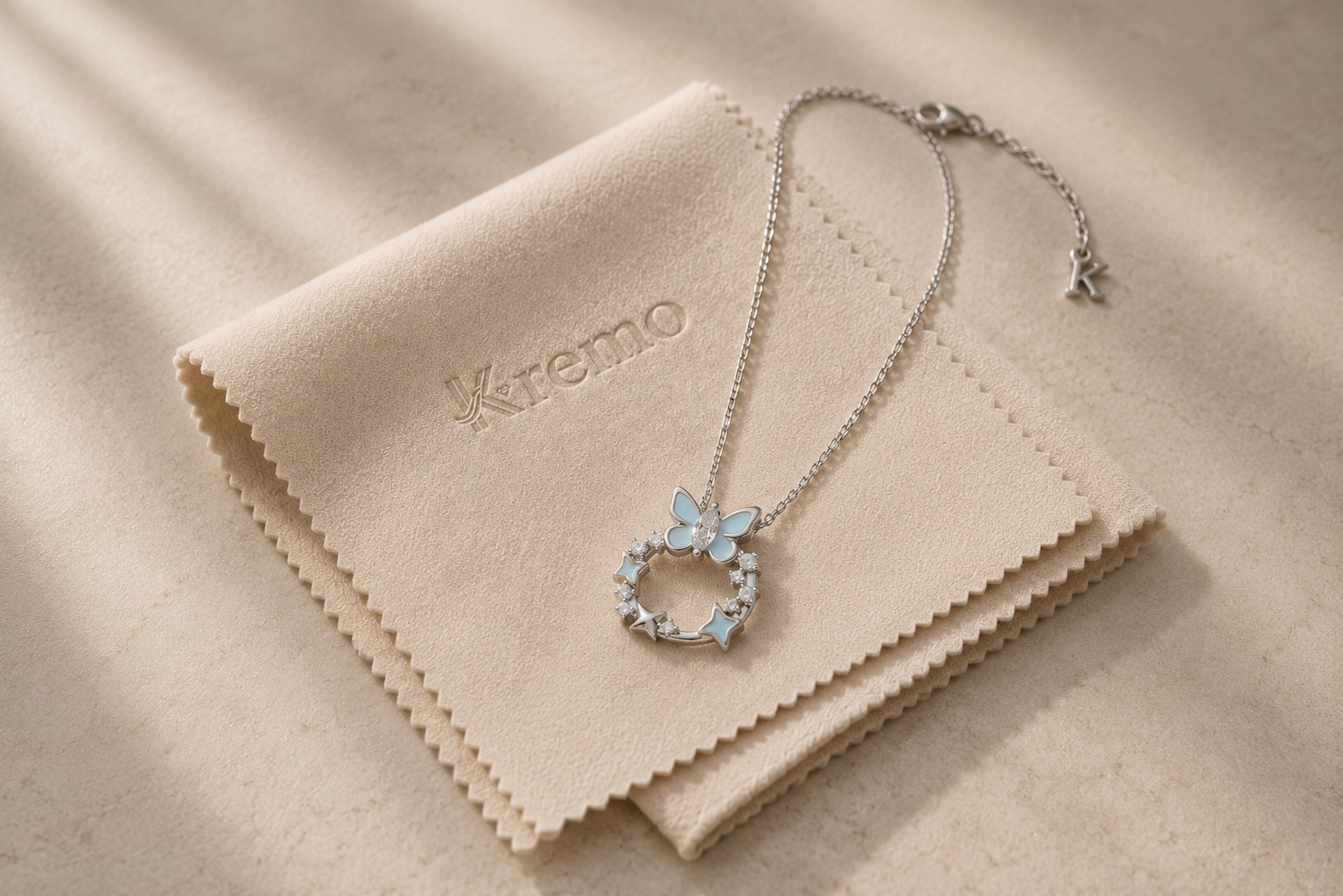 KREMO silver celestial necklace resting on a beige jewelry care cloth